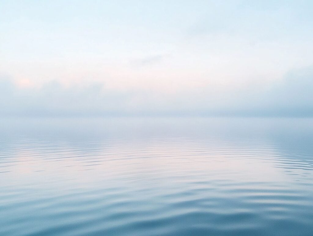 Calm lake under soft morning light with pale blue tones and gentle ripples, symbolizing reflection, hope, and emotional healing from depression.