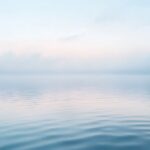 Calm lake under soft morning light with pale blue tones and gentle ripples, symbolizing reflection, hope, and emotional healing from depression.