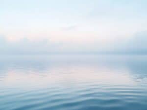Calm lake under soft morning light with pale blue tones and gentle ripples, symbolizing reflection, hope, and emotional healing from depression.