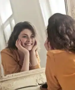 woman smiling at herself in the mirror