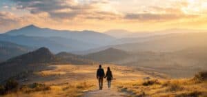 A couple walking hand in hand on a mountain path, viewed from behind, with soft golden light and open landscape symbolizing hope and reconnection