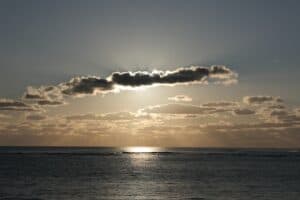 Sun emerging from clouds over a calm ocean, symbolizing hope and healing through EMDR therapy