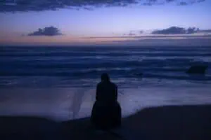 Person meditating with shadows behind them, representing risks of spiritual bypass in psychedelic therapy.