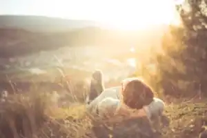 person lying on grassy hill above town