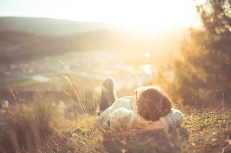 person lying on grassy hill above town