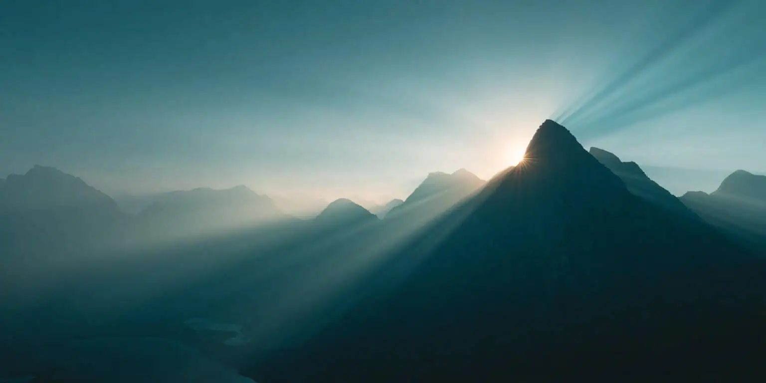 Sunlight breaking through mountain clouds over a calm landscape, symbolizing healing and transformation in Ketamine Therapy.