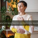Coping With Social Rejection and Relationship Wounding | Catalyst Center Person sitting quietly by a window, holding their chest gently, reflecting after an experience of social rejection.