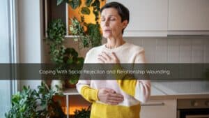 Person sitting quietly by a window, holding their chest gently, reflecting after an experience of social rejection.