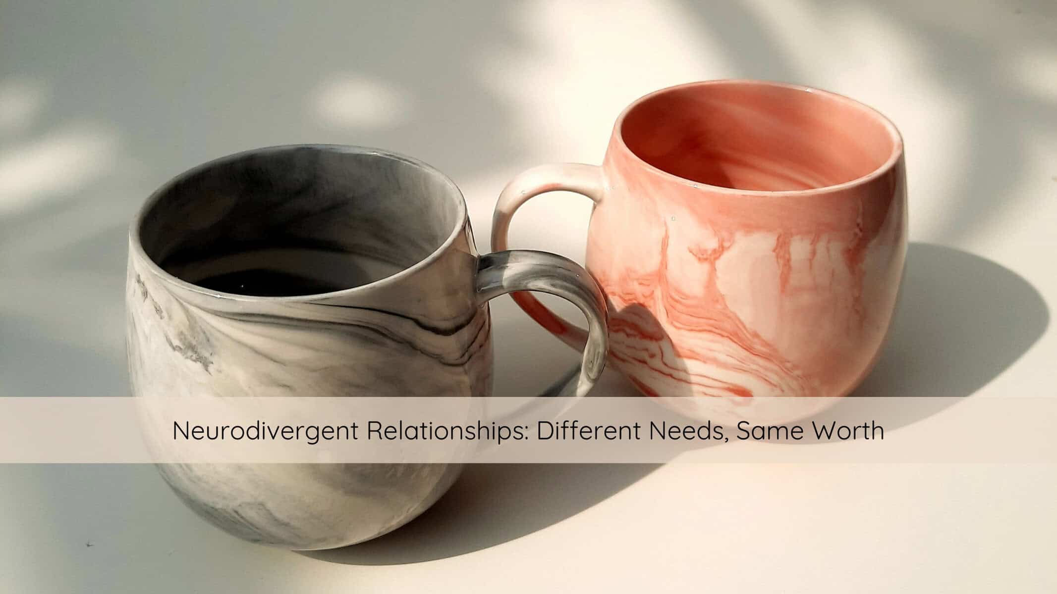 Two mugs resting side by side on a wooden table in soft natural light, symbolizing connection and companionship in neurodivergent relationships.