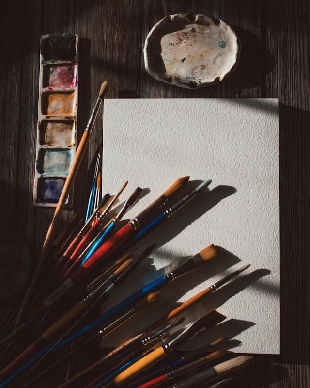 Open watercolor palette with a brush resting on paper, evoking gentle creative exploration after meditation